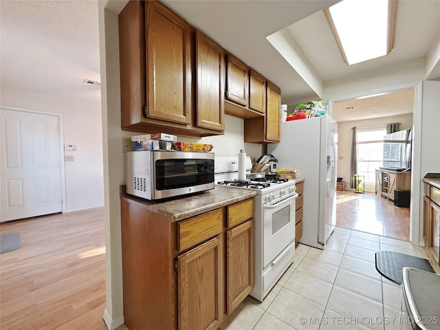301 S Division St, Sapulpa, OK 74066 - kitchen featuring white appliances, brown cabinetry, and light tile patterned floors