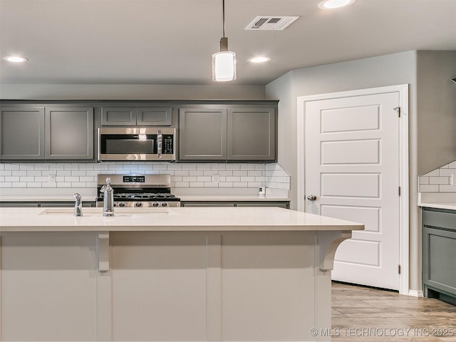 3604 E Quebec St, Broken Arrow, OK 74014 - kitchen featuring appliances with stainless steel finishes, gray cabinets, light countertops, tasteful backsplash, and hanging light fixtures