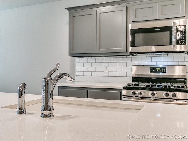 3604 E Quebec St, Broken Arrow, OK 74014 - kitchen featuring stainless steel appliances, gray cabinetry, tasteful backsplash, and light countertops