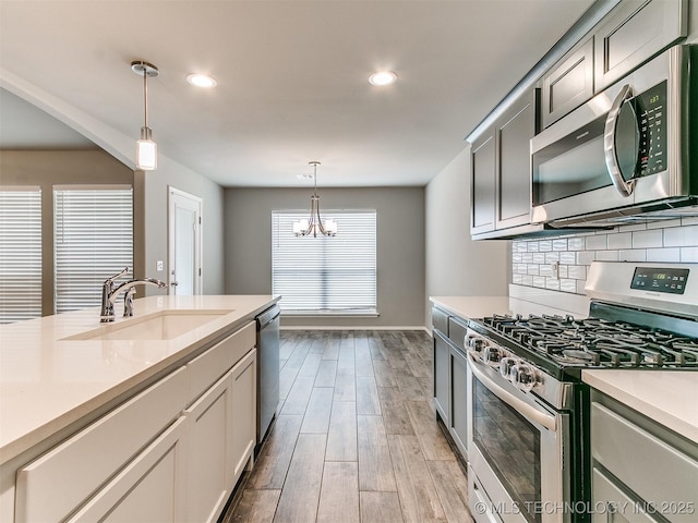 3604 E Quebec St, Broken Arrow, OK 74014 - kitchen featuring appliances with stainless steel finishes, light countertops, light wood-type flooring, hanging light fixtures, and a chandelier