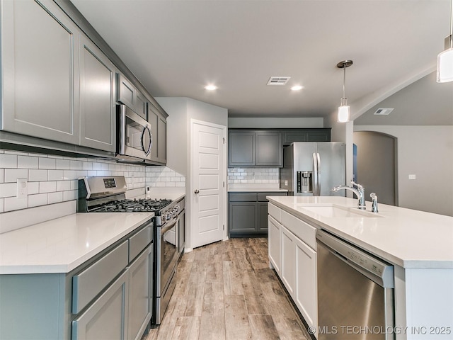 3604 E Quebec St, Broken Arrow, OK 74014 - kitchen with stainless steel appliances, arched walkways, light wood-style floors, tasteful backsplash, and light countertops
