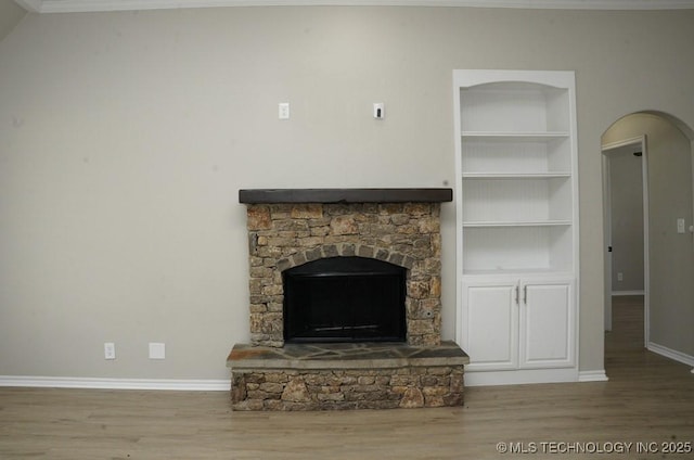 11906 S Nandina St, Jenks, OK 74037 - unfurnished living room featuring built in features, wood finished floors, arched walkways, a stone fireplace, and crown molding