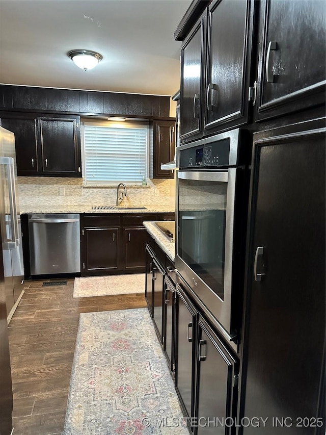 5908 S 68th E Ave, Tulsa, OK 74145 - kitchen with appliances with stainless steel finishes, wood finished floors, backsplash, and dark cabinetry