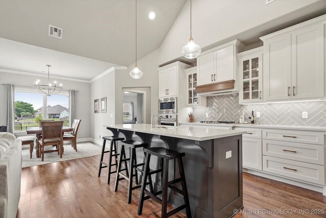 14305 S College Ave, Bixby, OK 74008 - kitchen with stainless steel appliances, a center island with sink, light countertops, a kitchen breakfast bar, and decorative backsplash