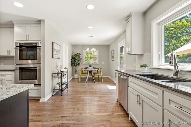 5861 S Hudson Pl, Tulsa, OK 74135 - kitchen with stainless steel appliances, light wood-style floors, recessed lighting, dark stone countertops, and a chandelier