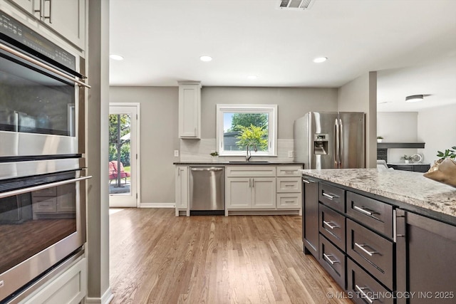 5861 S Hudson Pl, Tulsa, OK 74135 - kitchen with appliances with stainless steel finishes, healthy amount of natural light, light wood finished floors, white cabinets, and recessed lighting