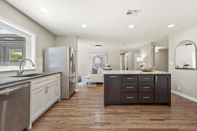 5861 S Hudson Pl, Tulsa, OK 74135 - kitchen with stainless steel appliances, white cabinetry, light wood finished floors, light stone counters, and a center island