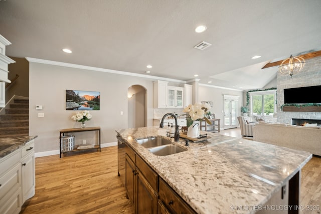 11802 S New Haven Ave, Tulsa, OK 74137 - kitchen with arched walkways, a stone fireplace, light wood finished floors, crown molding, and recessed lighting