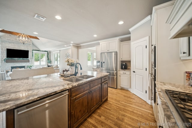 11802 S New Haven Ave, Tulsa, OK 74137 - kitchen featuring appliances with stainless steel finishes, light wood-style floors, light stone counters, crown molding, and range hood