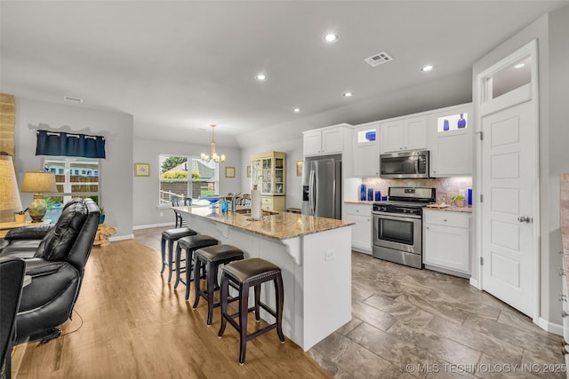 3331 Bunker St, Claremore, OK 74019 - kitchen with appliances with stainless steel finishes, a chandelier, white cabinetry, a breakfast bar area, and recessed lighting