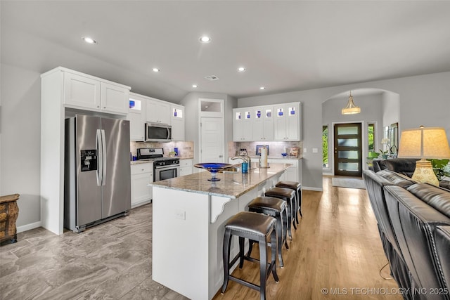 3331 Bunker St, Claremore, OK 74019 - kitchen featuring stainless steel appliances, arched walkways, white cabinets, backsplash, and recessed lighting