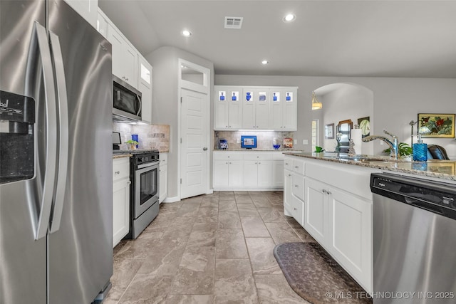 3331 Bunker St, Claremore, OK 74019 - kitchen featuring stainless steel appliances, arched walkways, tasteful backsplash, white cabinetry, and recessed lighting
