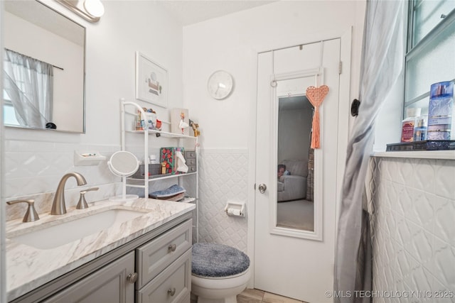 4647 S 30th W Ave, Tulsa, OK 74107 - bathroom with tile walls, wainscoting, vanity, and plenty of natural light
