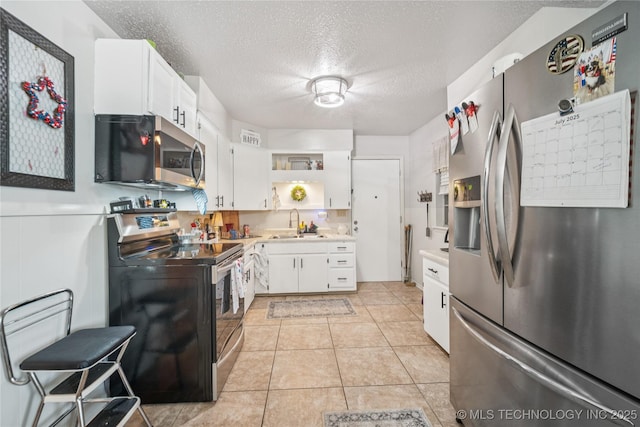 4647 S 30th W Ave, Tulsa, OK 74107 - kitchen with stainless steel appliances, open shelves, a textured ceiling, light countertops, and white cabinets