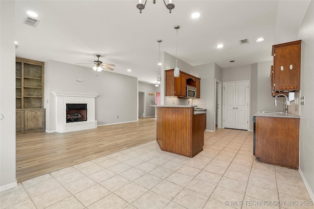 9005 N 154th E Ct, Owasso, OK 74055 - kitchen with stainless steel microwave, ceiling fan, light tile patterned floors, brown cabinetry, and open floor plan
