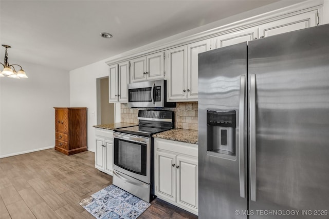 4350 E 74th Pl, Tulsa, OK 74136 - kitchen with appliances with stainless steel finishes, backsplash, a chandelier, dark stone countertops, and wood finished floors