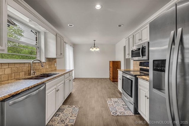 4350 E 74th Pl, Tulsa, OK 74136 - kitchen with stainless steel appliances, a chandelier, tasteful backsplash, light wood-style flooring, and white cabinets