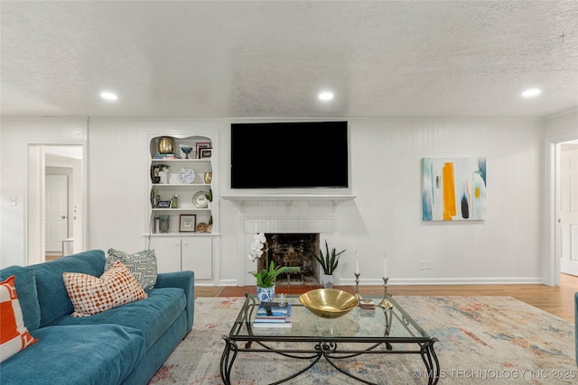 1640 E 41st St, Tulsa, OK 74105 - living area with wood finished floors, a textured ceiling, a fireplace, recessed lighting, and built in shelves