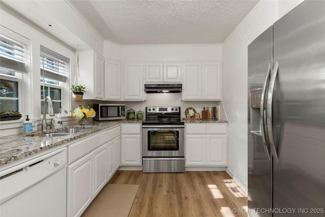 1640 E 41st St, Tulsa, OK 74105 - kitchen with appliances with stainless steel finishes, under cabinet range hood, a textured ceiling, white cabinets, and light wood-style floors