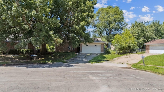 12131 E 32nd Pl, Tulsa, OK 74146 - view of property hidden behind natural elements with a garage, brick siding, and driveway