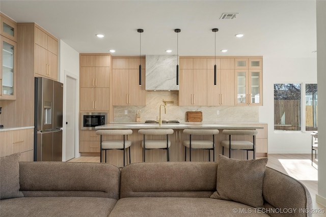 1732 S Jamestown Ave, Tulsa, OK 74112 - kitchen featuring stainless steel fridge with ice dispenser, light brown cabinetry, open floor plan, premium range hood, and a breakfast bar