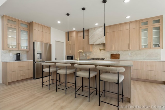 1732 S Jamestown Ave, Tulsa, OK 74112 - kitchen featuring appliances with stainless steel finishes, light brown cabinets, tasteful backsplash, light wood finished floors, and a kitchen bar
