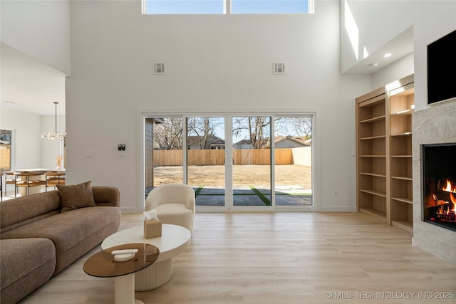 1732 S Jamestown Ave, Tulsa, OK 74112 - living room with a high ceiling, a tiled fireplace, light wood-style flooring, plenty of natural light, and built in features
