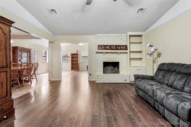 1508 Melissa Cir, Sapulpa, OK 74066 - living room featuring lofted ceiling, ceiling fan, a textured ceiling, dark wood-type flooring, and a brick fireplace
