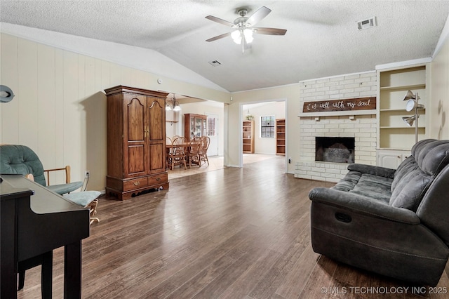 1508 Melissa Cir, Sapulpa, OK 74066 - living area featuring a ceiling fan, dark wood finished floors, vaulted ceiling, a textured ceiling, and a brick fireplace
