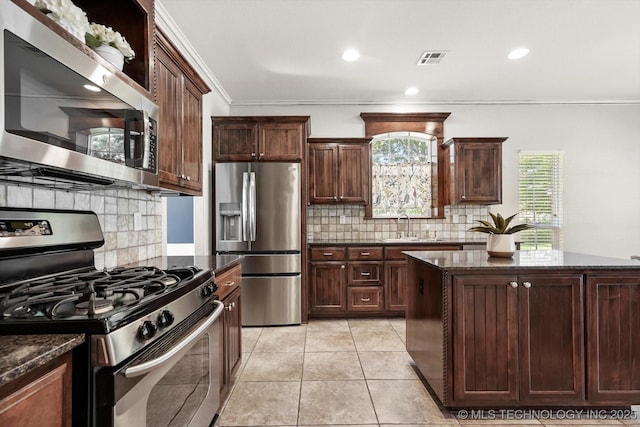7185 N 194th E Ave, Owasso, OK 74055 - kitchen featuring appliances with stainless steel finishes, ornamental molding, backsplash, dark stone countertops, and dark brown cabinetry