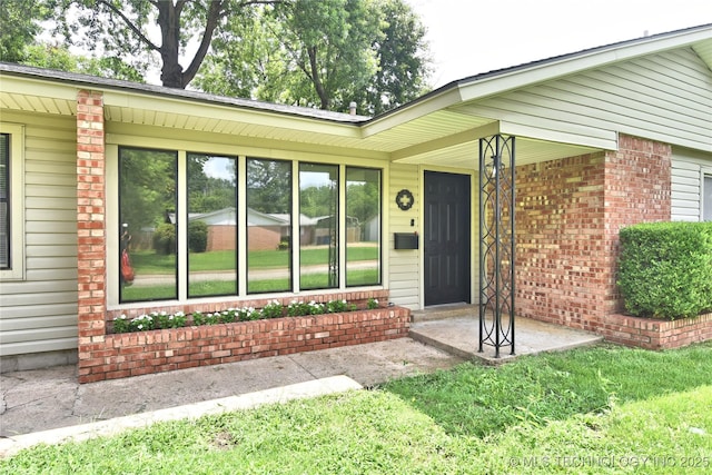5701 S Rockford Pl, Tulsa, OK 74105 - view of exterior entry with brick siding, a porch, and a lawn