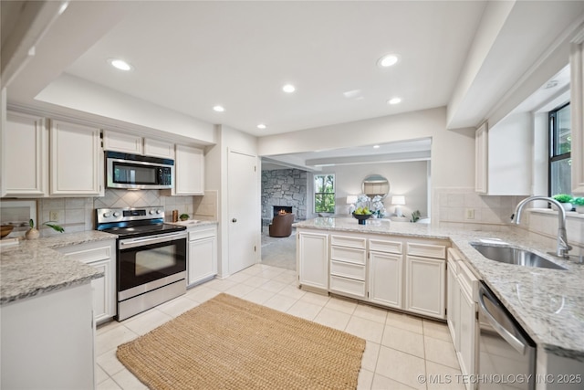 8912 S 70th E Ave, Tulsa, OK 74133 - kitchen with stainless steel appliances, a peninsula, backsplash, light stone counters, and light tile patterned floors