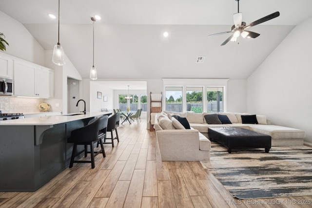 7413 N 160th E Ave, Owasso, OK 74055 - living room with light wood-style flooring, ceiling fan, and high vaulted ceiling
