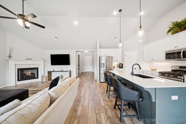 7413 N 160th E Ave, Owasso, OK 74055 - living area featuring ceiling fan, light wood finished floors, a glass covered fireplace, and high vaulted ceiling