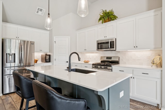 7413 N 160th E Ave, Owasso, OK 74055 - kitchen featuring appliances with stainless steel finishes, decorative backsplash, a kitchen breakfast bar, a center island with sink, and high vaulted ceiling