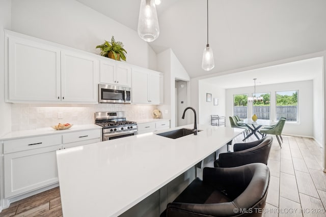 7413 N 160th E Ave, Owasso, OK 74055 - kitchen with stainless steel appliances, tasteful backsplash, an island with sink, vaulted ceiling, and white cabinetry