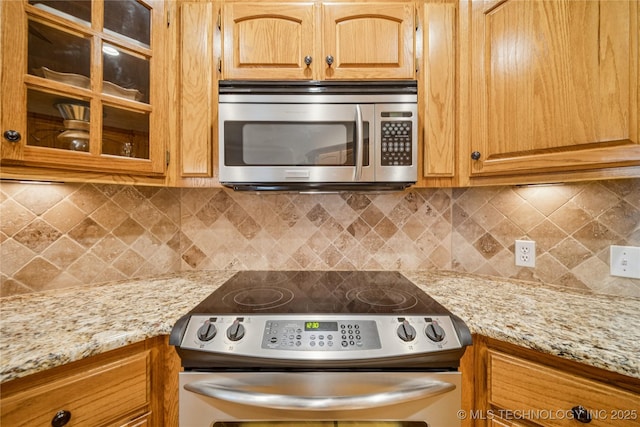 7534 S Hudson Pl, Tulsa, OK 74136 - kitchen with appliances with stainless steel finishes, glass insert cabinets, light stone counters, and tasteful backsplash
