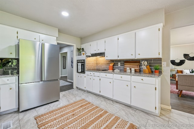 3350 E 54th St, Tulsa, OK 74135 - kitchen with freestanding refrigerator, tasteful backsplash, white cabinets, black electric cooktop, and light marble finish floors