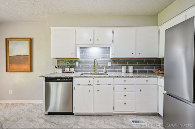 3350 E 54th St, Tulsa, OK 74135 - kitchen with appliances with stainless steel finishes, light stone counters, white cabinetry, backsplash, and light marble finish flooring