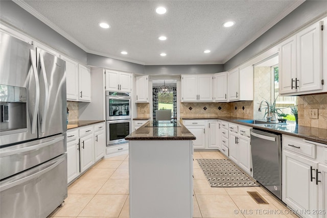 9622 S Maplewood Ave, Tulsa, OK 74137 - kitchen featuring appliances with stainless steel finishes, a kitchen island, a textured ceiling, ornamental molding, and white cabinetry