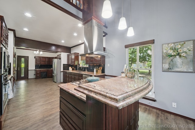 10102 N 147th E Ave, Owasso, OK 74055 - kitchen featuring island exhaust hood, stainless steel appliances, light countertops, backsplash, and wood finished floors