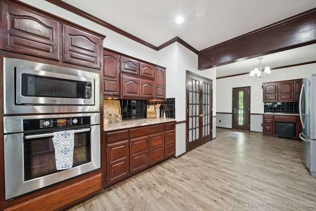 10102 N 147th E Ave, Owasso, OK 74055 - kitchen with stainless steel appliances, light wood-type flooring, decorative backsplash, a chandelier, and ornamental molding
