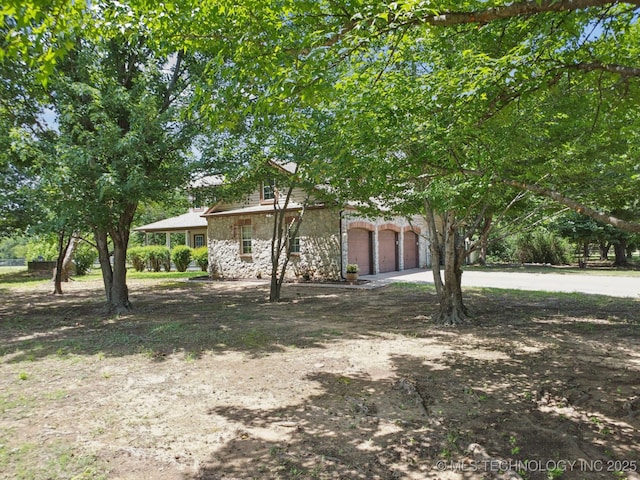 10102 N 147th E Ave, Owasso, OK 74055 - view of side of home featuring stone siding, concrete driveway, and a garage