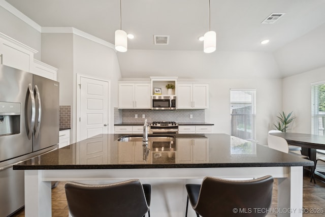 2618 W 115th St S, Jenks, OK 74037 - kitchen with stainless steel appliances, vaulted ceiling, backsplash, white cabinetry, and a kitchen island with sink
