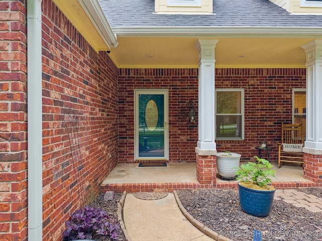 4852 E Redbud Dr, Claremore, OK 74019 - view of exterior entry with a shingled roof, brick siding, and covered porch