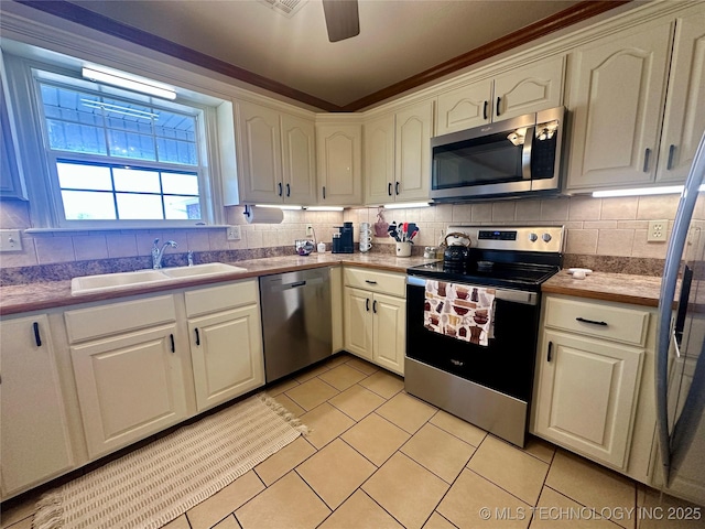 215 Belt St, Eufaula, OK 74432 - kitchen with appliances with stainless steel finishes, light tile patterned floors, backsplash, a ceiling fan, and white cabinetry