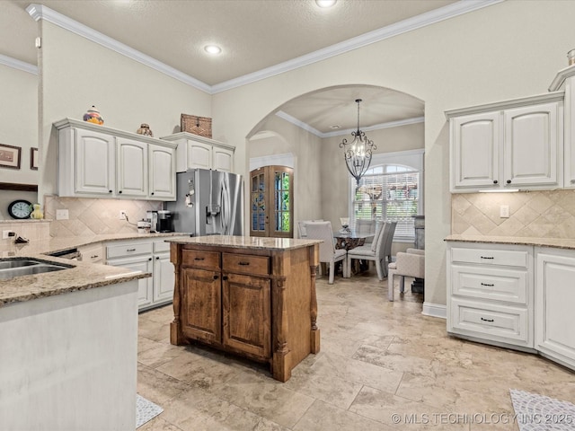 5719 Nottingham Pl, Bartlesville, OK 74006 - kitchen featuring arched walkways, stainless steel fridge with ice dispenser, light stone countertops, backsplash, and ornamental molding