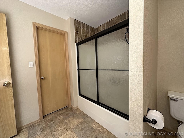 1530 Persimmon, Ardmore, OK 73401 - bathroom featuring shower / bath combination with glass door, stone finish floors, and a textured ceiling