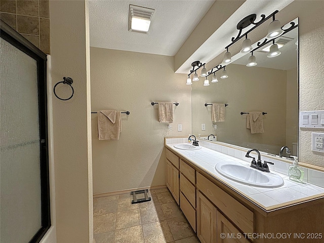 1530 Persimmon, Ardmore, OK 73401 - full bath featuring double vanity, a textured wall, and a shower with door
