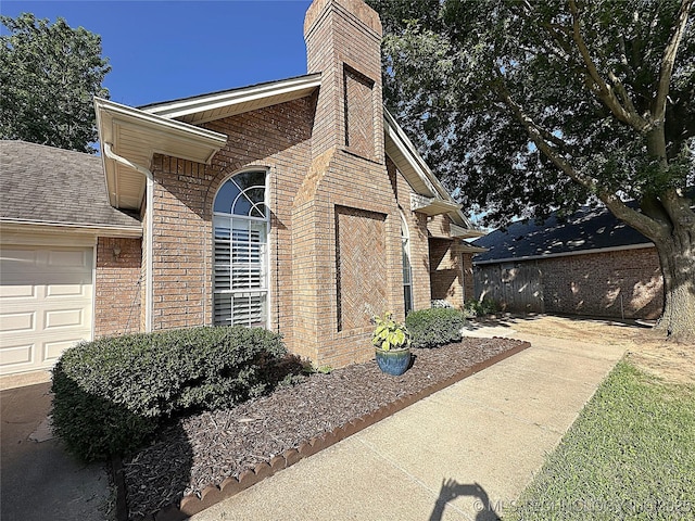 1530 Persimmon, Ardmore, OK 73401 - view of home's exterior with an attached garage, brick siding, and a chimney
